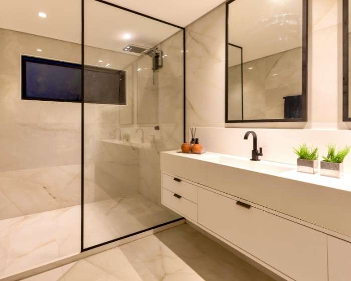 western sydney bathroom renovation service Walk-in shower with a black-framed glass screen, marble-look tiles and a floating white vanity