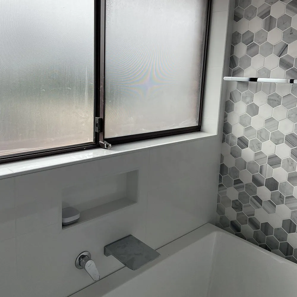 full bathroom reconfigurations Built-in bath with a wall spout, shower niche and grey hexagon feature tiles below a frosted window